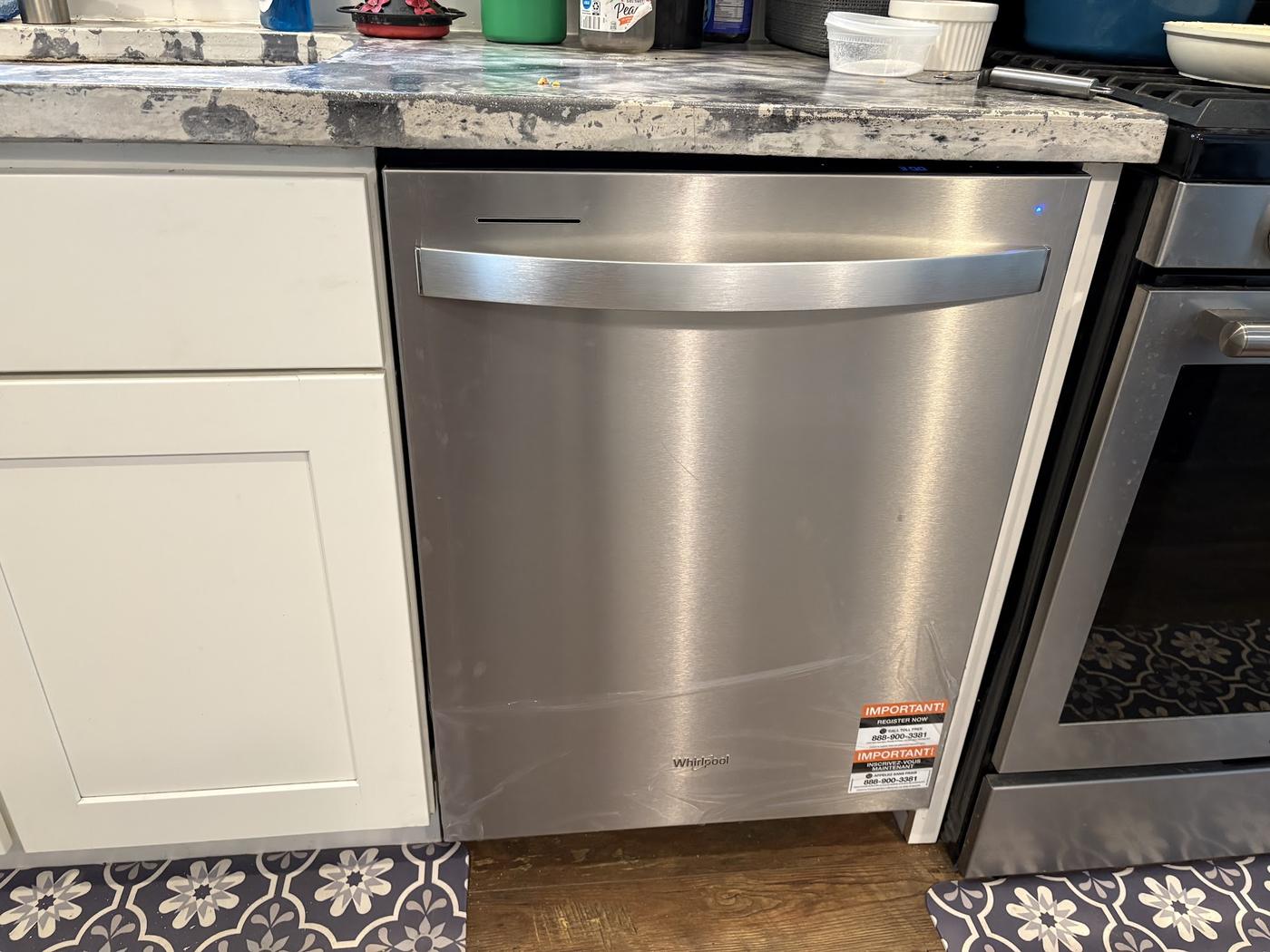 A newly installed dishwasher, protective film still on the door